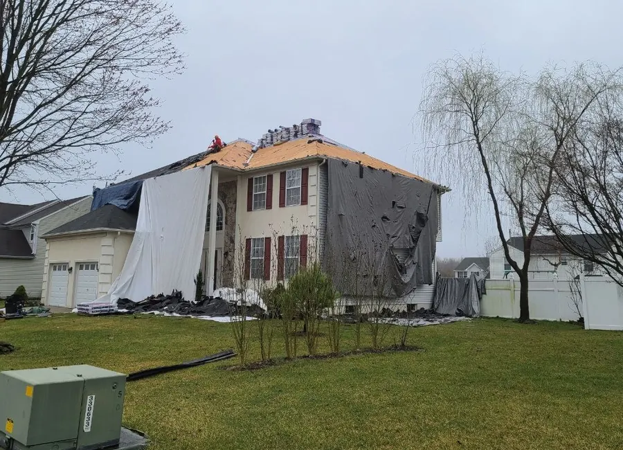 Colonial home mid tear-off with landscaping tarped